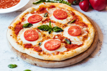 Classic Pizza with basil and tomato on top places on a bright background