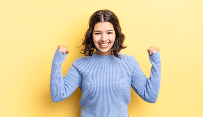 young pretty girl feeling happy, positive and successful, celebrating victory, achievements or good...