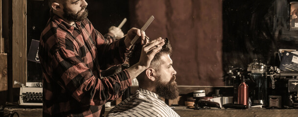 Hairdresser cutting hair of male client. Hairstylist serving client at barber shop. Man visiting hairstylist in barbershop. Bearded man in barbershop. Work in the barber shop. Man hairstylist.