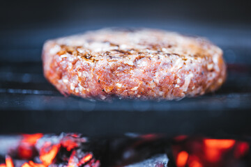 Burger meat on a charcoal barbecue