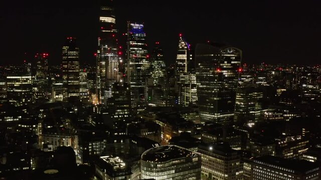 Slide and pan footage of night downtown panorama. Elevated view of skyscrapers in City financial hub. London, UK