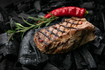 grilled steak on a background of black charcoal.
