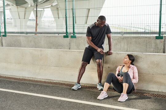 Young couple discussing exercises with each other during their training on the stadium