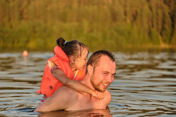 Father teaches daughter to swim. A child plays with his father during the summer vacation. A child...