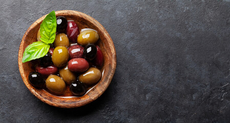 Various colorful olives with olive oil and basil