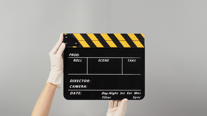 Naklejka premium Hand is holding yellow with black clapper board color and wear white medical glove