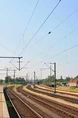 View of empty multiple train tracks from platform at Itzehoe train station in summer with clear and sunny blue sky background. No people. 