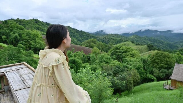Asian woman sitting on balcony and looking the view nature in rainforest on vacation