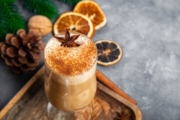 A glass of traditional Christmas drink eggnog on a gray background, copy space for text. Spicy drink made from egg and milk with cinnamon, cardamom.