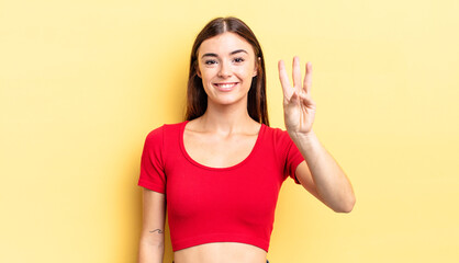 hispanic pretty woman smiling and looking friendly, showing number three or third with hand...