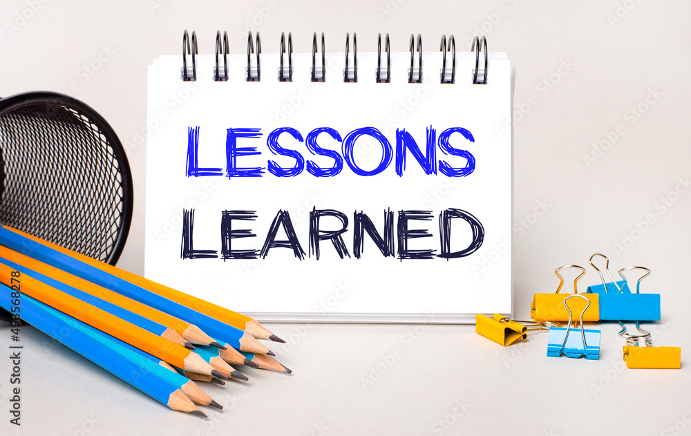 Poster on a light background, yellow and blue pencils and paper clips and a white notebook with the text le