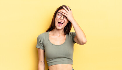 hispanic pretty woman laughing and slapping forehead like saying d’oh! I forgot or that was a...