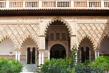 The arab style decorated facade in a patio of the famous Alcazar (meaning: fortress) in Seville,...