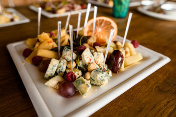 cheese snacks and nuts and berries on white square plate