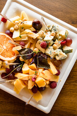 Close-up top view of cheese snacks and nuts and berries on white square plate