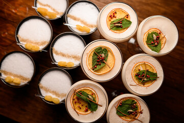top view of green leaves and berries that decorate white cocktail foam in glasses
