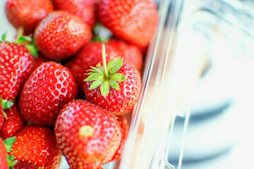 Top view closed up red strawberries in clear plastic box.