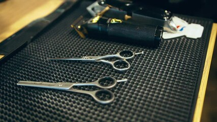 Hairdressing scissors and barber accessories in hair salon close up. Professional tools for haircut in barber shop. Hairdressing concept. Table with scissors and trimmers at the barber shop