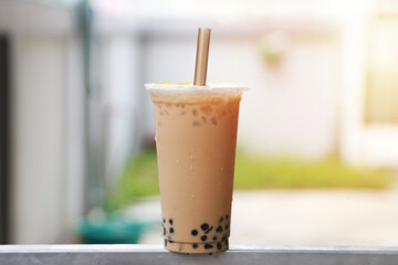 Ice milk tea and bubble boba in plastic cup put on bar steel and sun light