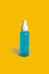 One Isolated Bottle of Blue Alcohol - Transparent Plastic Spray Bottle - Bright Vivid Yellow Background with Shadow - Disinfecting Sanitizer Antibacterial - Personal Hygiene