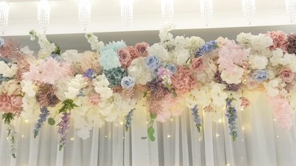 Flower arrangement is made by florist. Restaurant is decorated with bouquets of fresh flowers. Banquet hall with flower arrangements. Exquisite reception. Roses, hydrangeas, flowering cherry branches