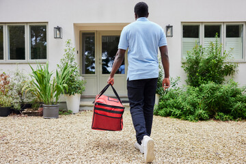 Rear View Of Gig Economy Driver Delivering Online Takeaway Food Order To House