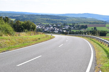 gewundene Eifelstraße in ein kleine Dorf im Tal