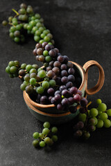 grape bunches in ceramic cups on gray background