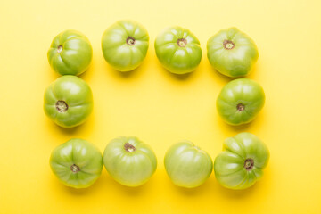 Green tomatoes for conservation on a yellow background. Unripe tomatoes for harvesting.