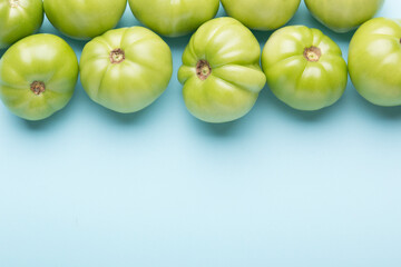 Green tomatoes for conservation on a blue background. Unripe tomatoes for harvesting.