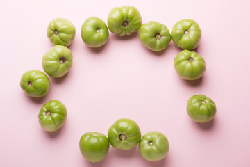 Green tomatoes for preservation on a pink background. Unripe tomatoes for harvesting.