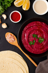 Beetroot hummus, with tahini, spices and olive oil, on a black background, no people, top view,