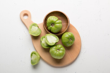 Green tomatoes for conservation on a wooden board on a gray background. Unripe tomatoes for harvesting. Cutaway tomato.