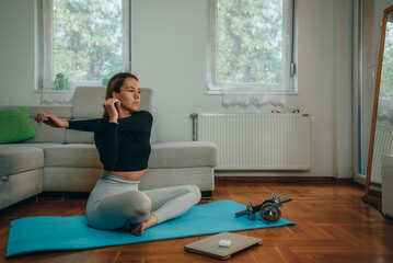 Woman stretching and using a laptop while training at home