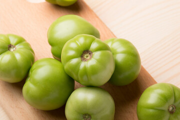 Green tomatoes for conservation on a wooden background. Unripe tomatoes for harvesting.
