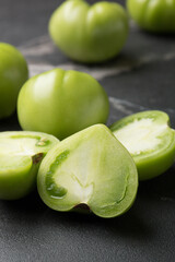 Green tomatoes for conservation on a dark marble background. Unripe tomatoes for harvesting. Cutaway tomatoes.