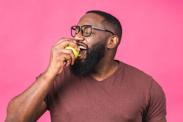 Healthy african american black man holding an apple isolated over pink background. Diet healthy food concept.