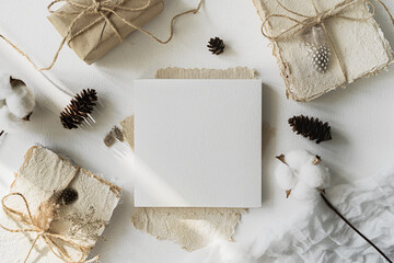 Notepad mockup for showcasing artwork and design. A notebook with an open blank page lies on a white table surrounded by dry plants. Minimal mock up of sketchbook or drawing paper.