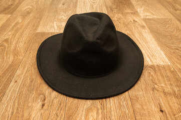 Fototapeta na wymiar Black men's stylish felt hat. Lies on the wooden floor.