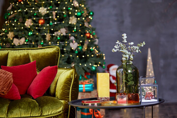 Home cozy Christmas decorations. Bright sofa with colorful pillows, decorated Christmas tree and Christmas decorations on the table. High quality photo.