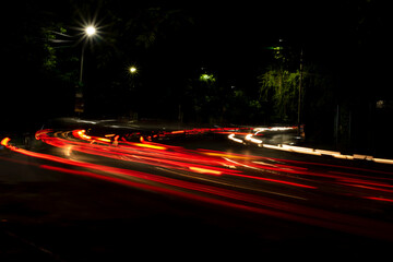 Fototapeta na wymiar Car Light trails on a city street in a dark black night. Photo is taken with long exposure.