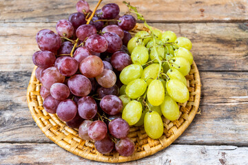 Bunches of red and yelloe grapes, on a rustic wooden base. 