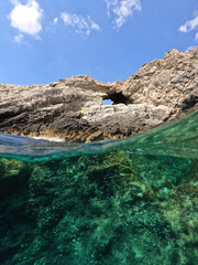 Underwater split photo of beautiful paradise pebble rocky bay of Kaladi with turquoise crystal clear sea and small caves, Kithira island, Ionian, Greece