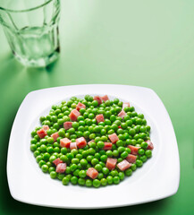Guisantes con  jamón serrano sobre fondo verde. Peas with serrano ham on a green background.
