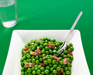 Guisantes con jamón serrano sobre fondo verde. Peas with serrano ham on a green background.
