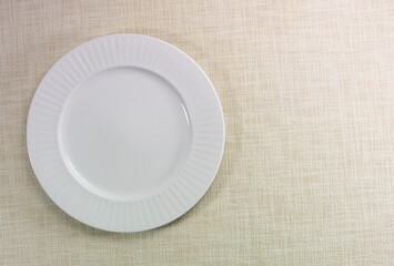 Plato blanco de porcelana sobre mantel de hilo . White porcelain plate on a linen tablecloth.