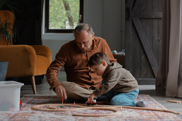 Grandfather play with a grandson on floor at home