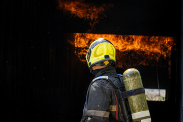 Fototapeta premium Fireman wearing suit for safety using water and extinguisher to fighting with fire flame in an emergency situation.