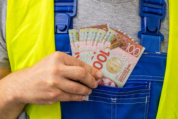 Worker counting his earnings, New Zealand  money, Concept of wages and labor costs in industry