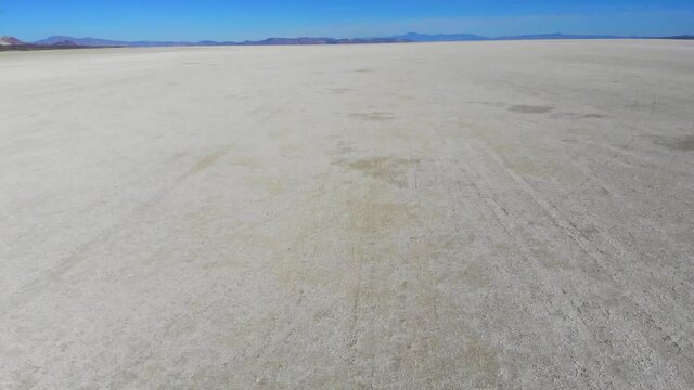 Back view from drone on automotive vehicle exploring desolate American death valley with scenery colorful skies on horizon, concept of travel on supercar with horsepower for drifting at salt flats
